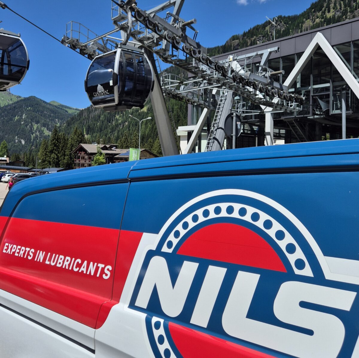 NILS-branded cableway vehicle beneath an alpine gondola lift